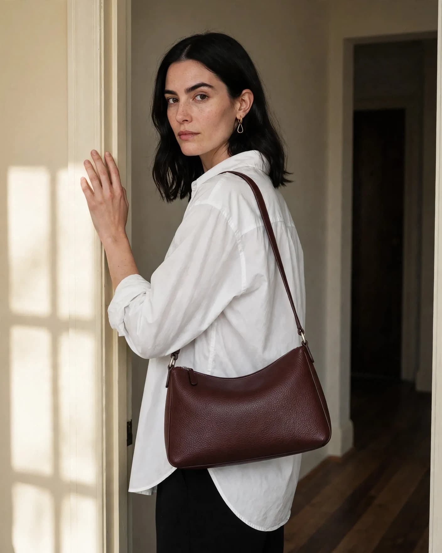 Same oxblood handbag carried by a woman through a sunlit residential doorway